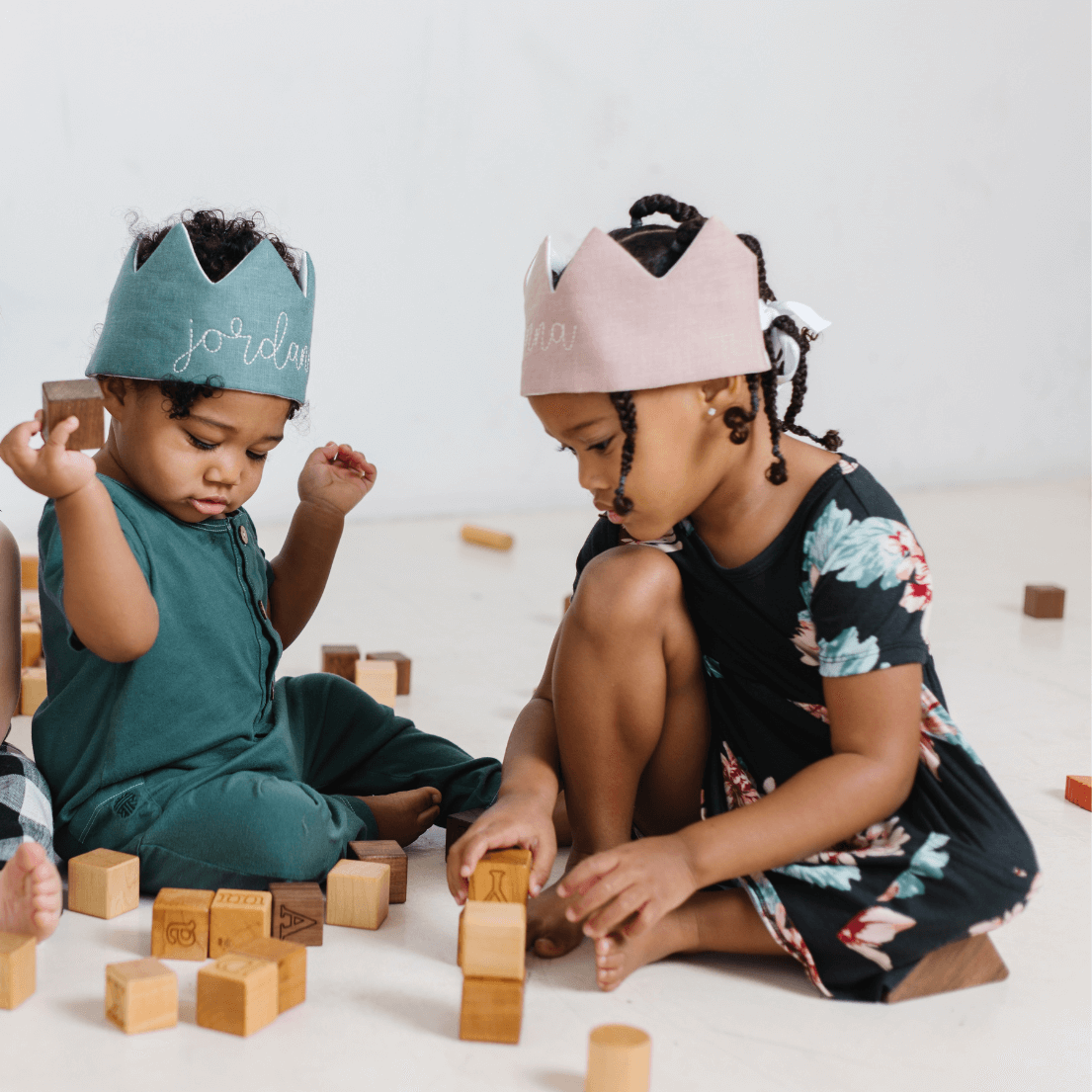 little girl and boy playing blocks and wearing dress up crowns