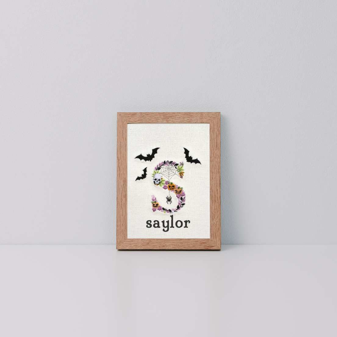 embroidered letter s in halloween font with saylor underneath in a frame