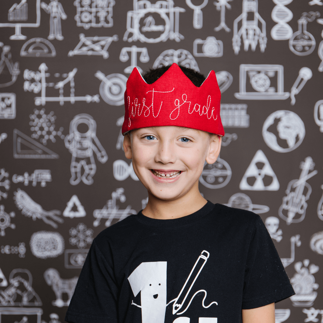 Smiling child wearing a red first grade embroidered crown for the first day of school photo prop