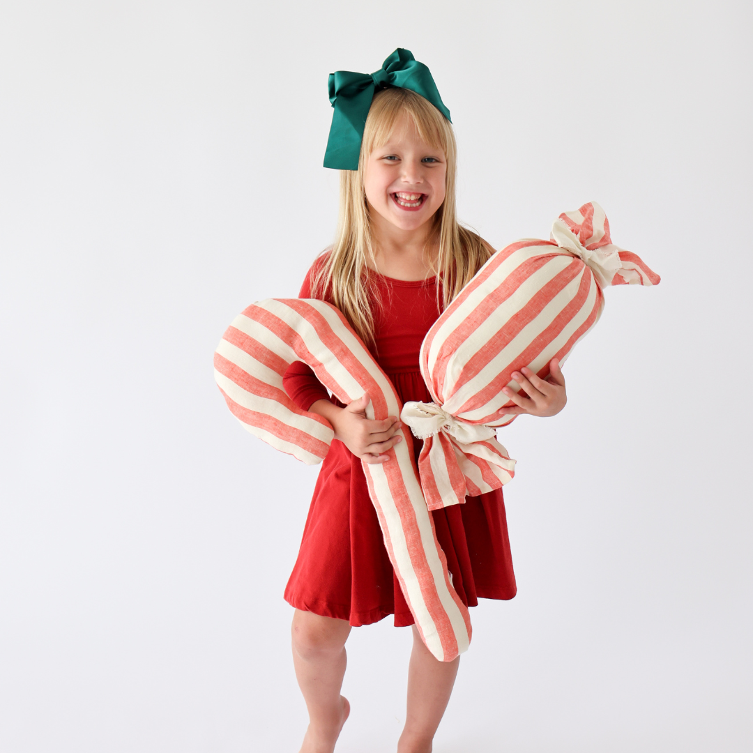 little girl holding christmas decor pillows shaped like candy from Madly Wish