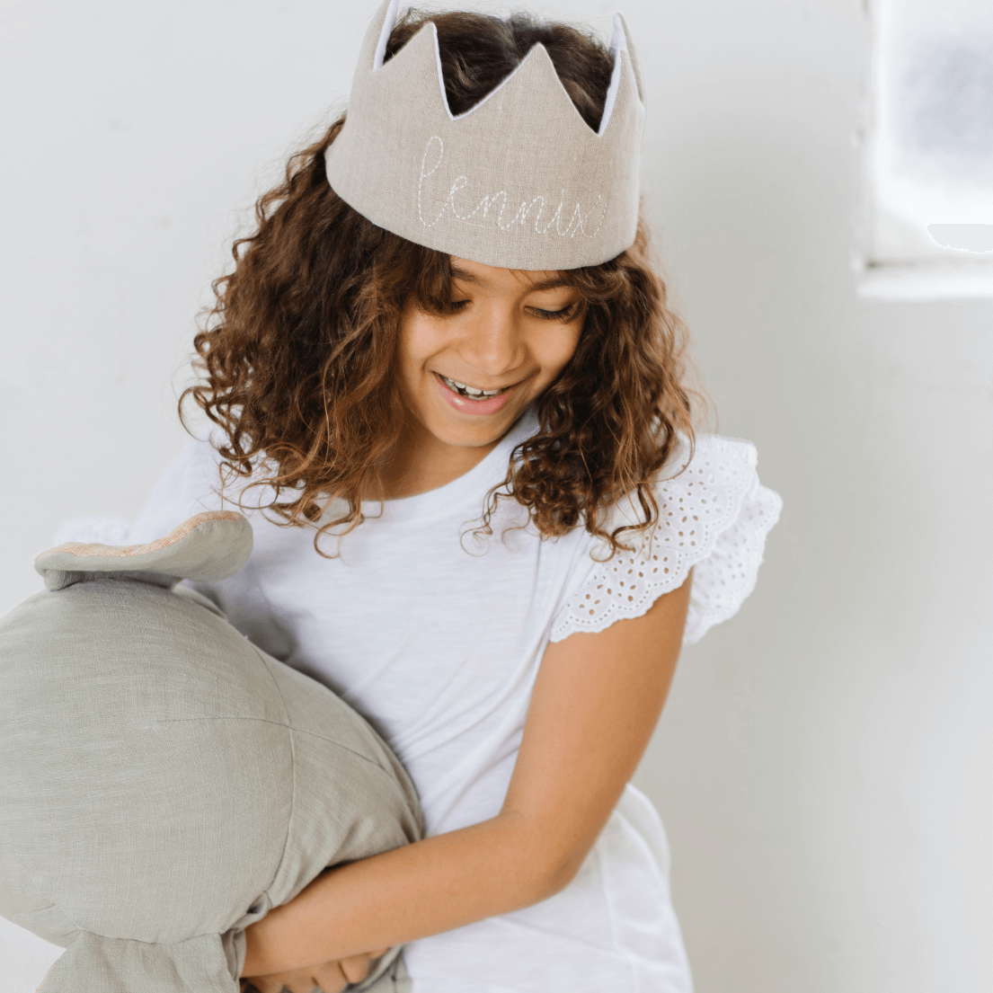 girl wearing a birthday crown and playing with a stuffed animal
