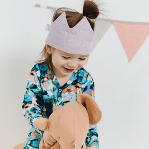 first birthday party with a little girl wearing a purple crown playing with a stuffed animal