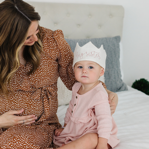 little girl wearing a crown sitting with pregnant mom