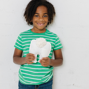 boy who just lost a tooth holding a tooth fairy pillow with a pocket